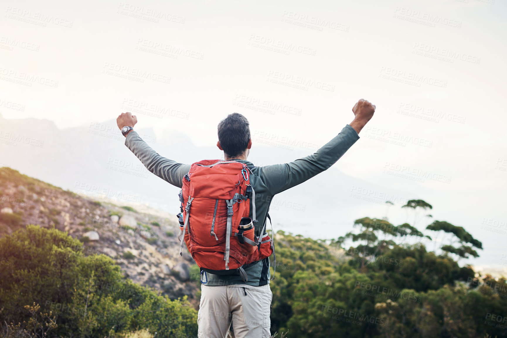 Buy stock photo Cropped shot of a cheerful young man lifting his arms in the air  and looking into the distance while going for a hike up a mountain
