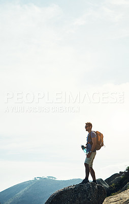 Buy stock photo Cropped shot of a carefree young man standing on top of a mountain after a day of hiking