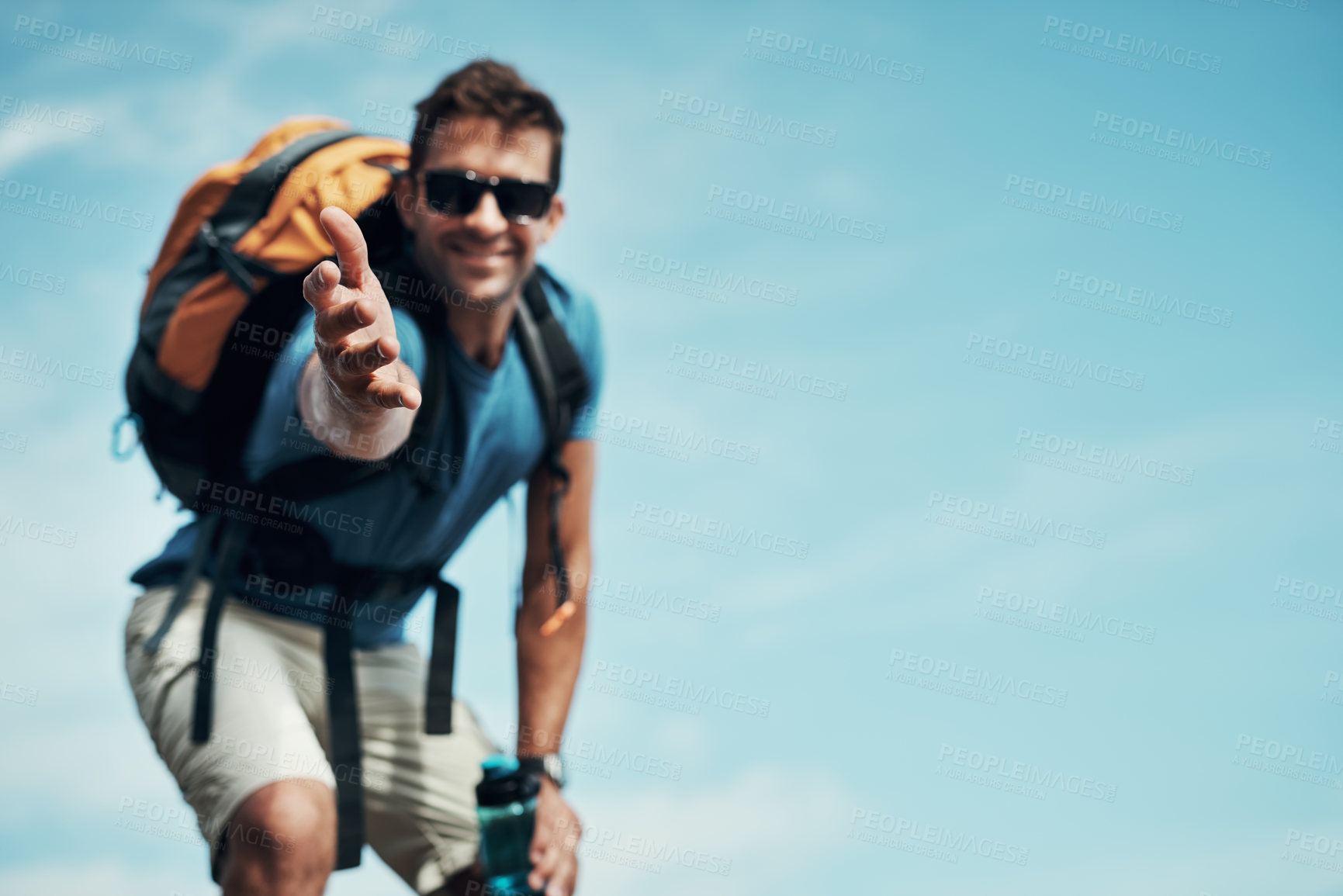 Buy stock photo Portrait of a cheerful young man stretching out his hand to help while going for a hike up a mountain