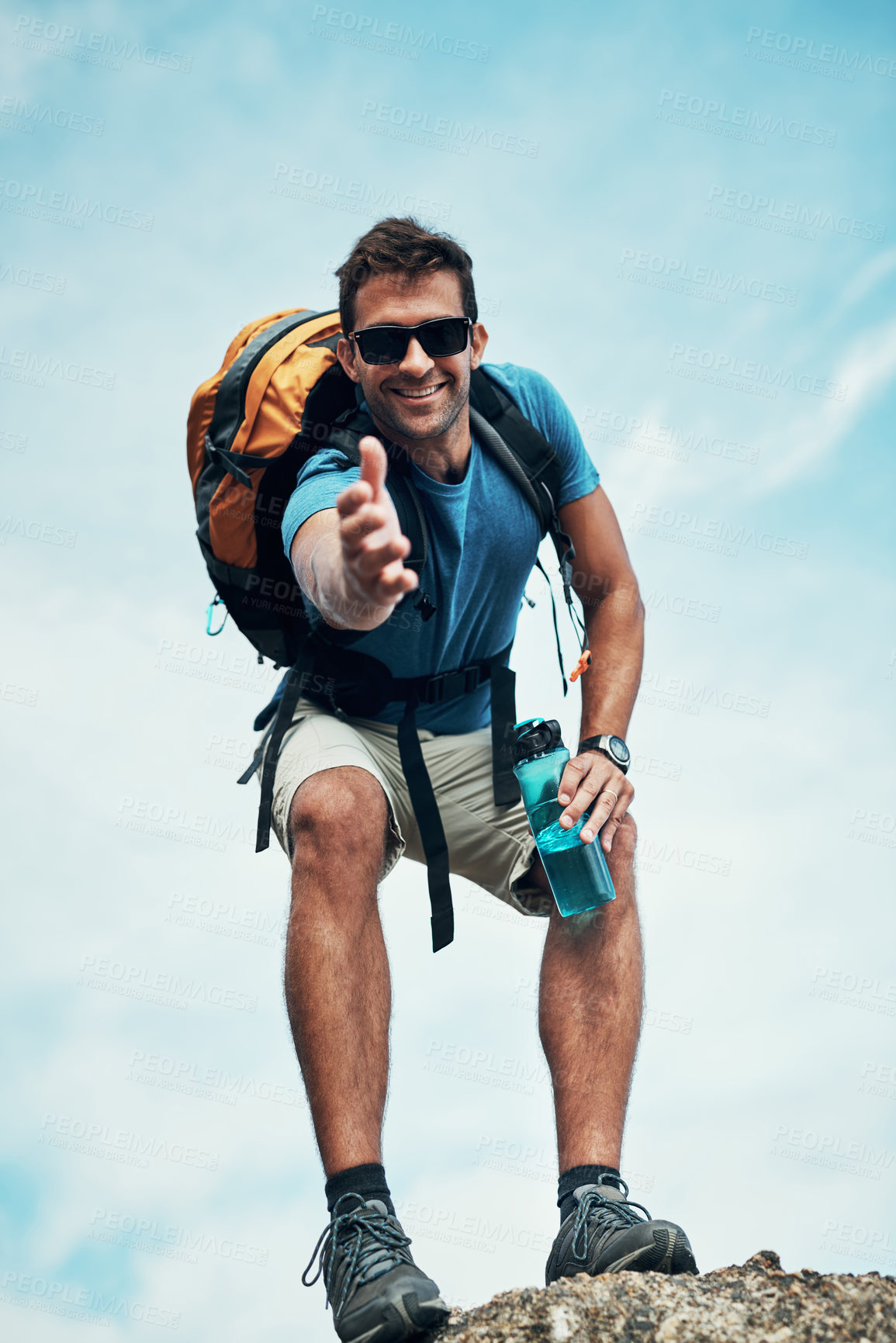 Buy stock photo Portrait of a cheerful young man stretching out his hand to help while going for a hike up a mountain