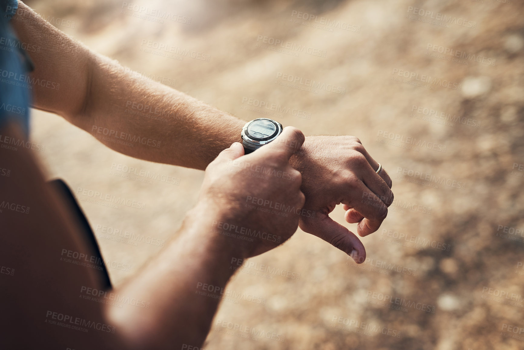 Buy stock photo Cropped shot of an unrecognizable man configuring his wristwatch while going for a hike up a mountain