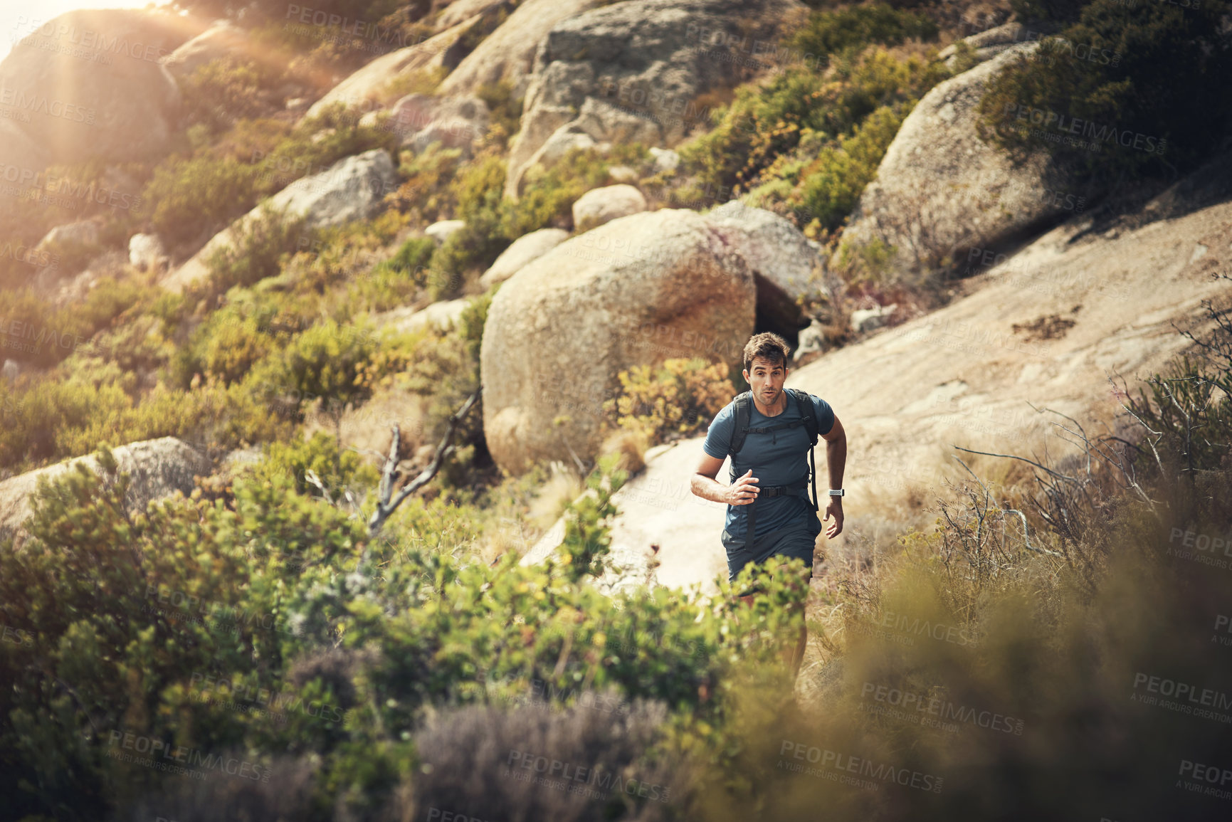 Buy stock photo Cropped shot of a handsome young man running during his hike in the mountains