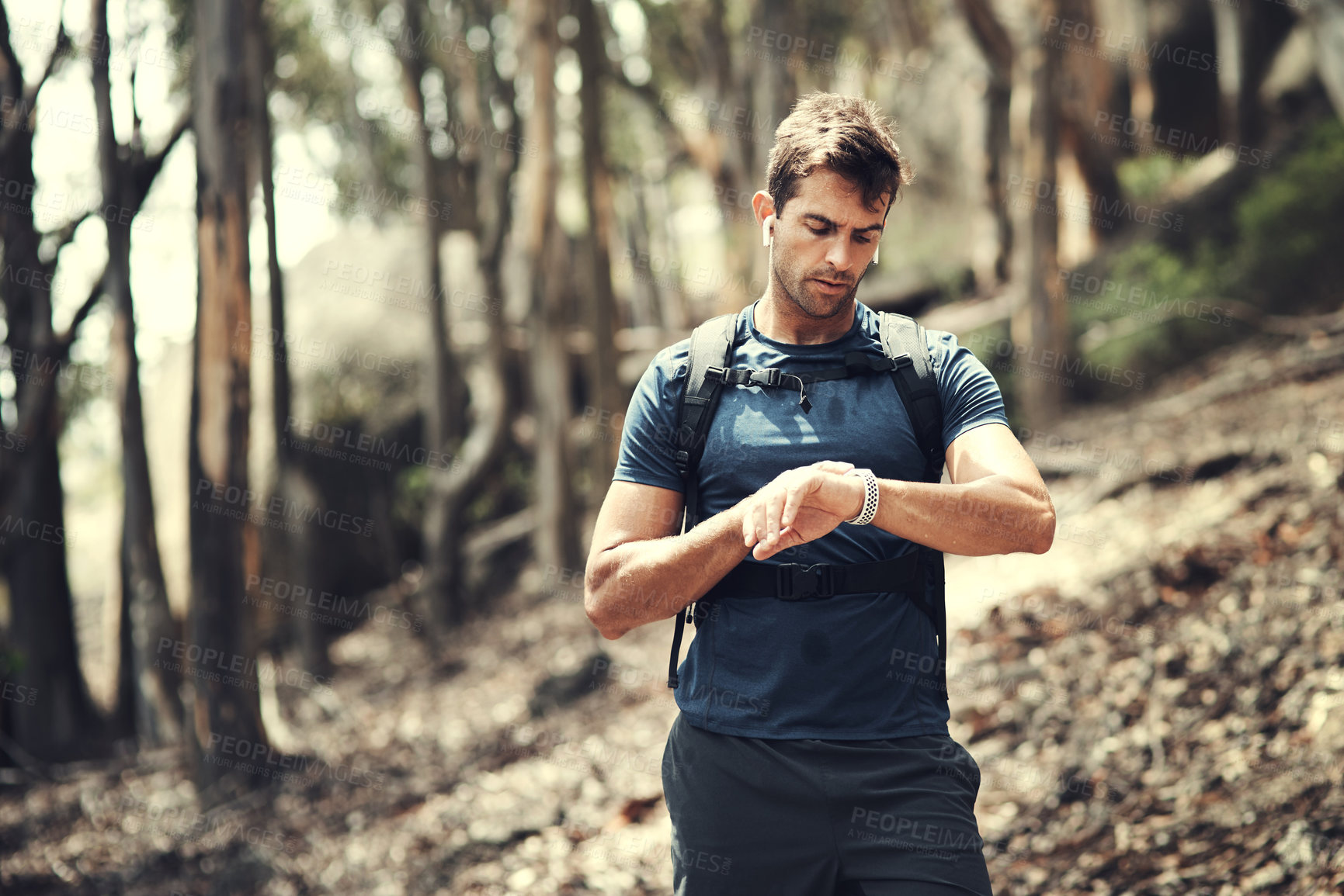 Buy stock photo Cropped shot of a handsome young man checking his watch while out hiking in the mountains