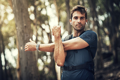 Buy stock photo Cropped shot of a handsome young man stretching before heading off on his hike in the mountains