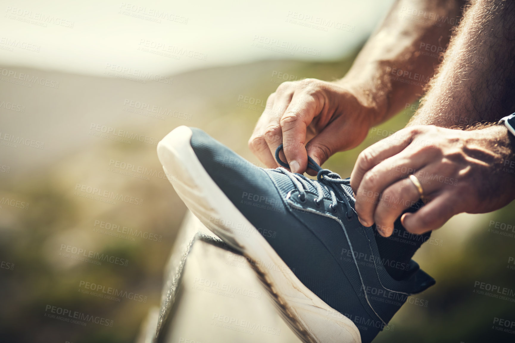 Buy stock photo Cropped shot of an unrecognizable young man tying his laces during a hike in the mountains