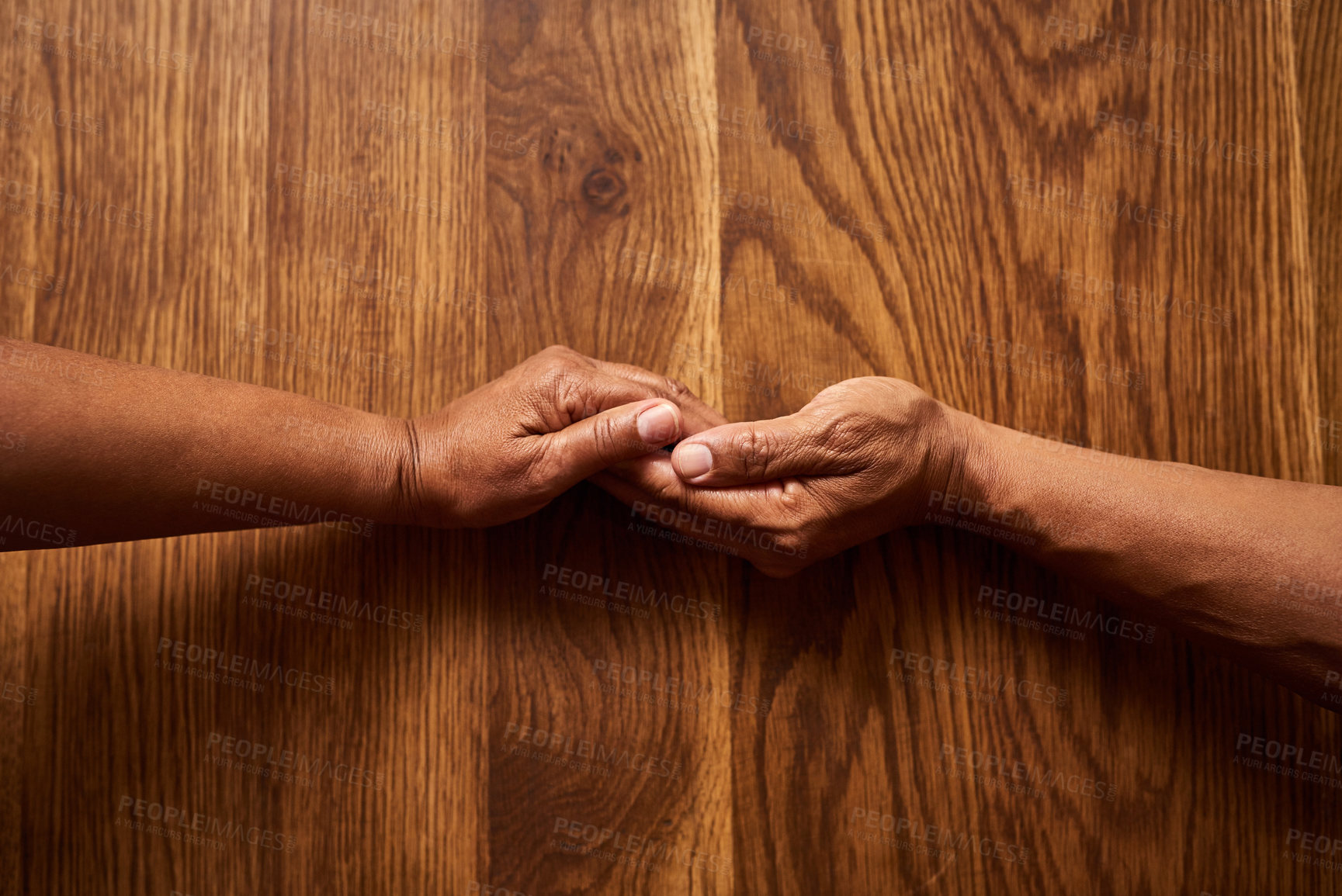 Buy stock photo High angle shot of an unrecognizable senior couple holding hands together over a wooden table at home