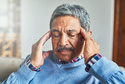 Buy stock photo Shot of a senior man suffering from a headache at home