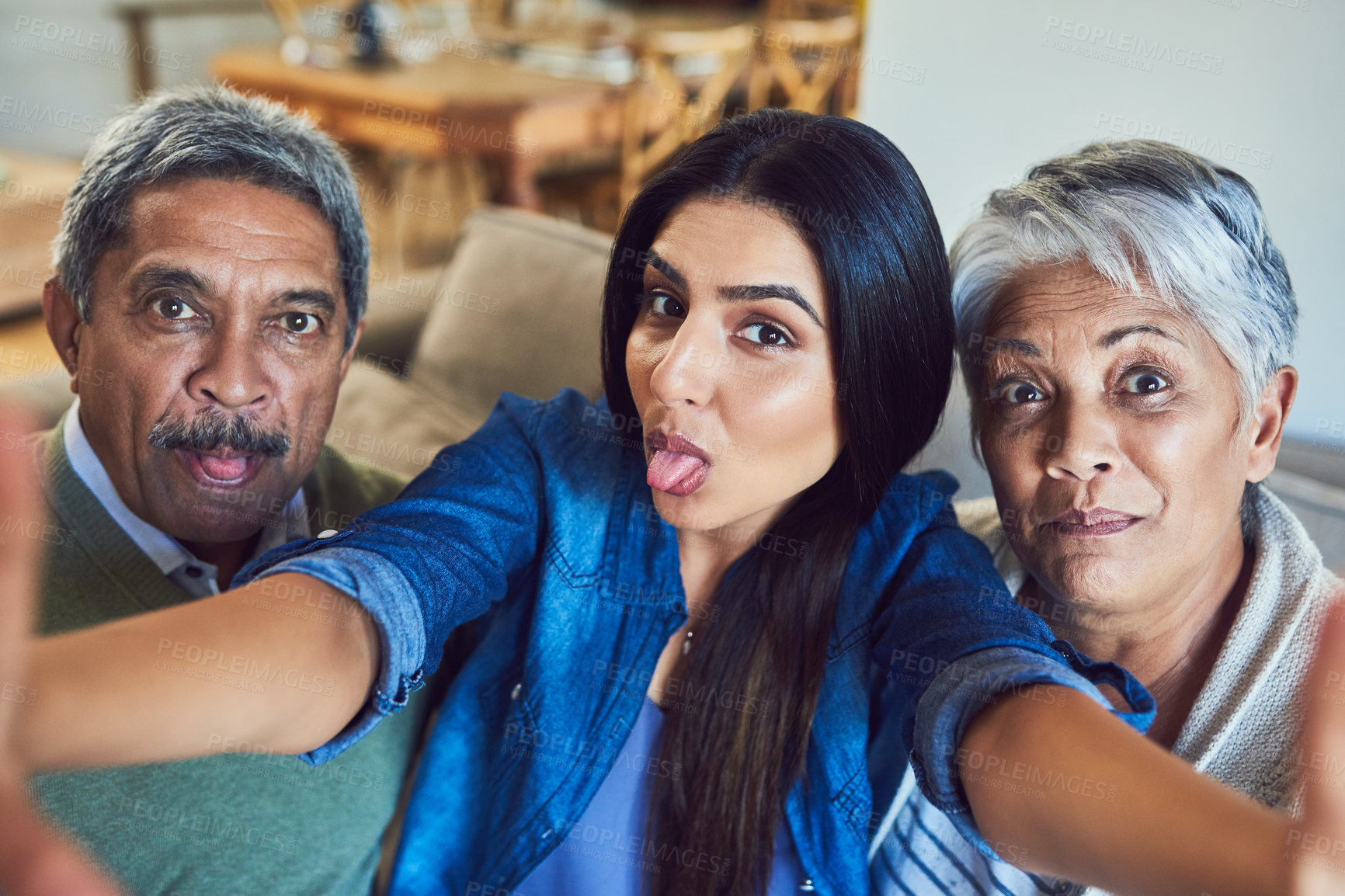 Buy stock photo Shot of a cheerful senior couple and their daughter taking a selfie together while sitting on a couch at home