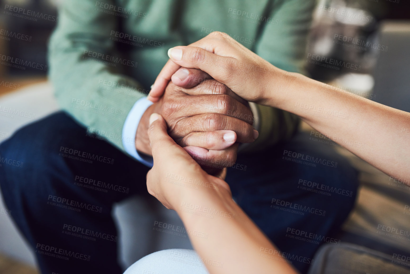 Buy stock photo Shot of an unrecognizable senior man holding hands with his daughter while sitting on a couch at home