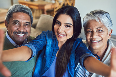 Buy stock photo Portrait of a cheerful senior couple and their daughter taking a selfie together while sitting on a couch at home
