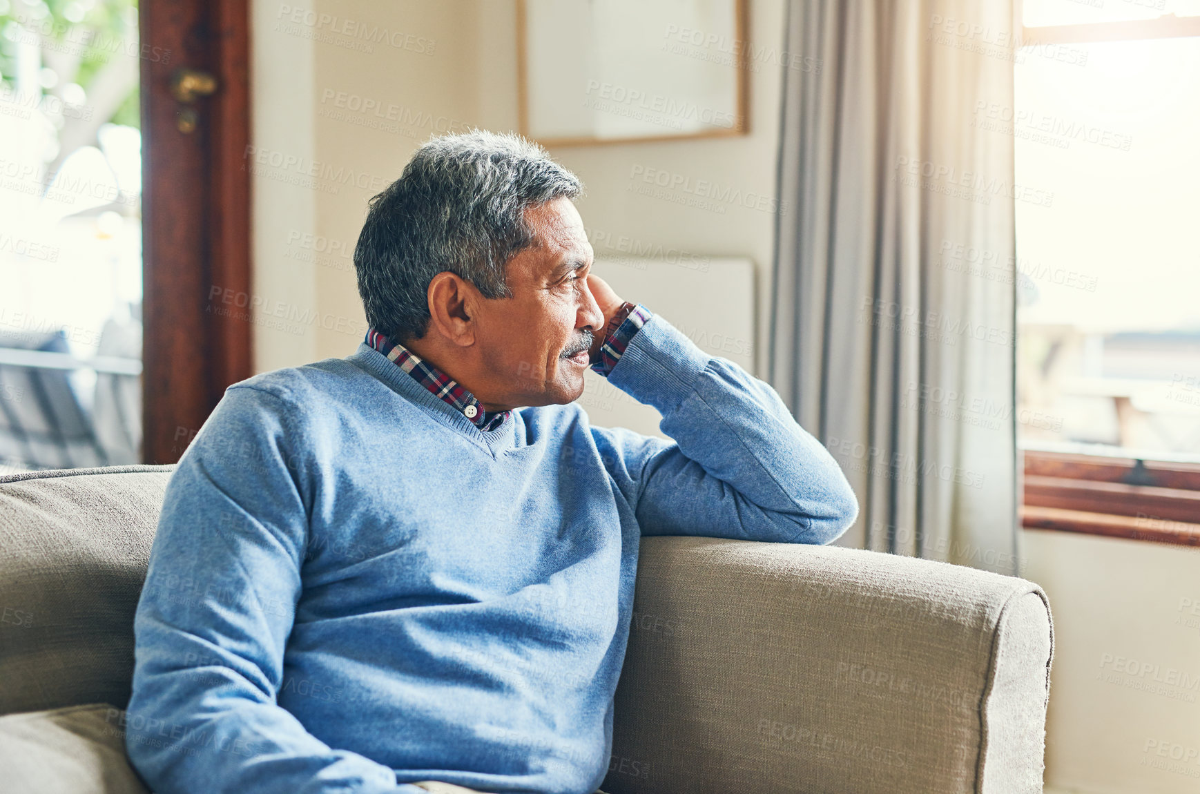 Buy stock photo Shot of a senior man looking very thoughtful while relaxing on a sofa at home