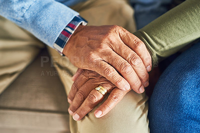 Buy stock photo Shot of an unrecognizable senior couple holding hands together while sitting on a couch at home