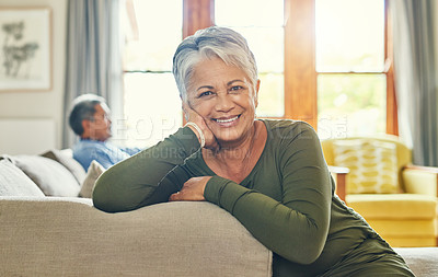 Buy stock photo Portrait of a beautiful senior woman relaxing on a couch with her husband in the background