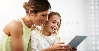Buy stock photo Shot of a beautiful young mother and her daughter using a digital tablet together at home