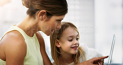 Buy stock photo Shot of a beautiful young mother and her daughter using a digital tablet together at home