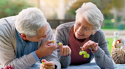 Buy stock photo Old couple, fruit and park picnic for relax summer or retirement bonding with nutrition, grapes or happy. Man, woman and eating on blanket in nature for romantic anniversary or holiday, food or love