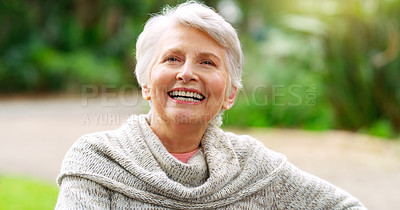Buy stock photo Cropped shot of a cheerful elderly woman seated on a bench outside in a park during the day