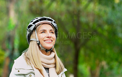 Buy stock photo Cropped shot of a cheerful young woman riding her bicycles outside in a park during the day