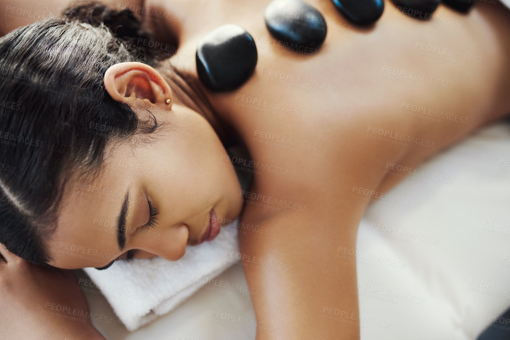 Buy stock photo Woman, relax and sleeping in rock massage at spa for skincare, beauty or body treatment at salon. Calm female asleep with eyes closed and hot rocks on back for healthy physical therapy at the resort