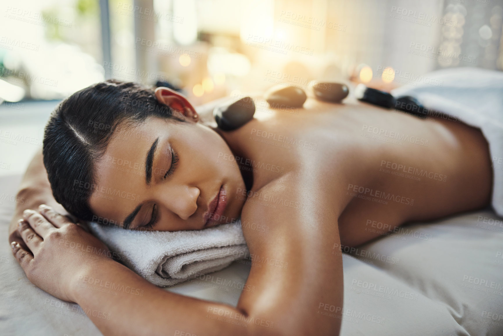 Buy stock photo Woman, relax and sleeping in rock massage for skincare, relaxation or beauty treatment on bed at spa. Female relaxing asleep with eyes closed with hot rocks on back for healthy body care at resort
