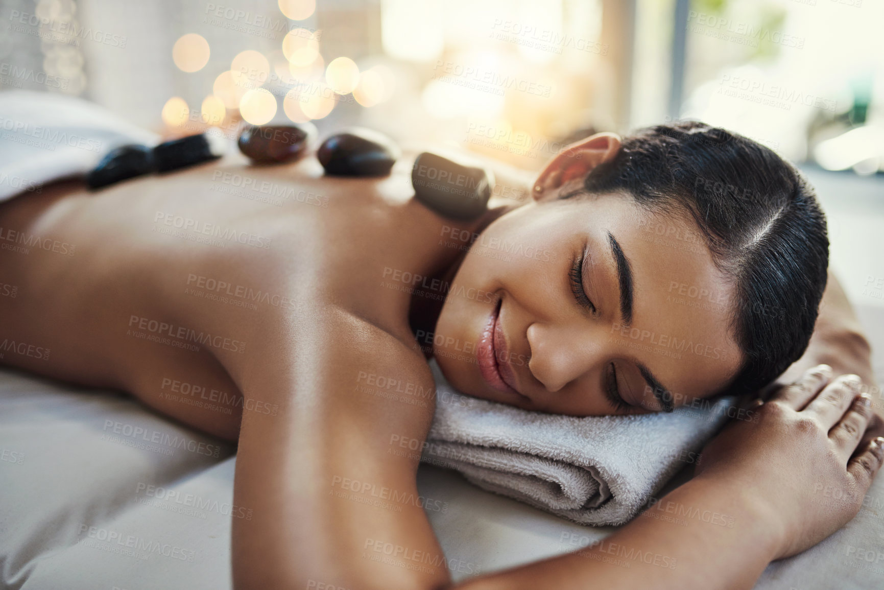 Buy stock photo Happy woman, relax and sleeping on bed at spa for rock massage, skincare or beauty treatment indoors. Calm female asleep with eyes closed and smile for hot rocks on back or body care at the resort