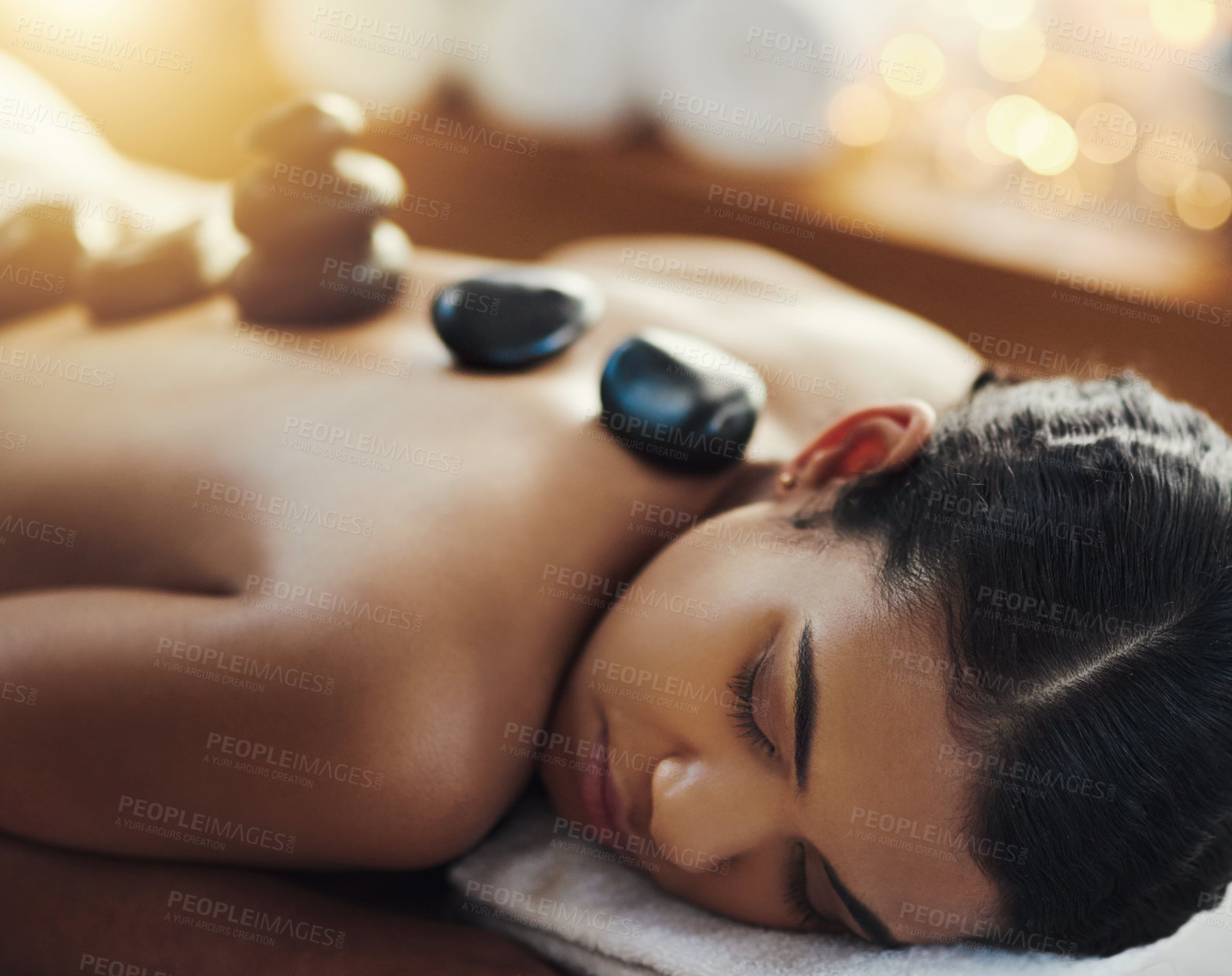 Buy stock photo Woman, relax and sleeping in rock massage at spa for skincare, beauty or body treatment at resort. Calm female asleep in relaxation with hot rocks or pile on back in therapy, zen or wellness at salon