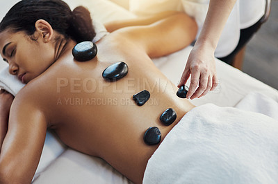 Buy stock photo Woman, hands and stone massage at spa for skincare, beauty or body treatment on bed at resort. Calm female lying in relaxation with masseuse, hot rocks and back for therapy, zen or wellness at salon