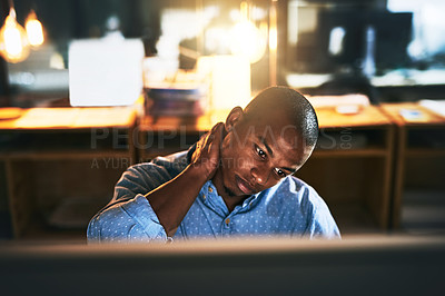 Buy stock photo Cropped shot of a handsome young businessman experiencing tension while using a computer late at work
