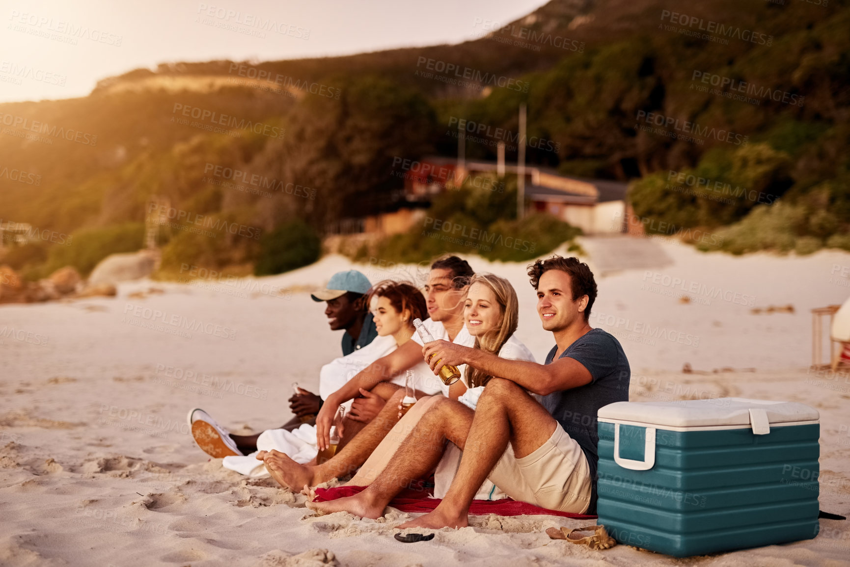 Buy stock photo Shot of a group of friends sitting together on the beach