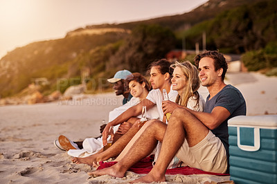 Buy stock photo Shot of a group of friends sitting together on the beach