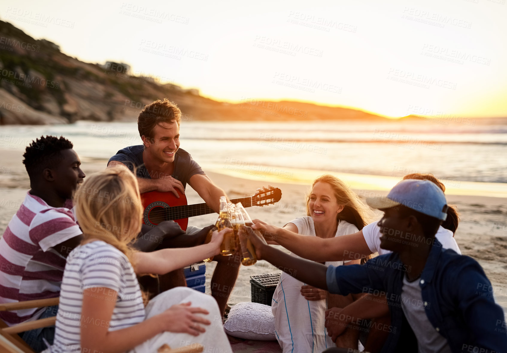 Buy stock photo Shot of a group of friends enjoying drinks on the beach