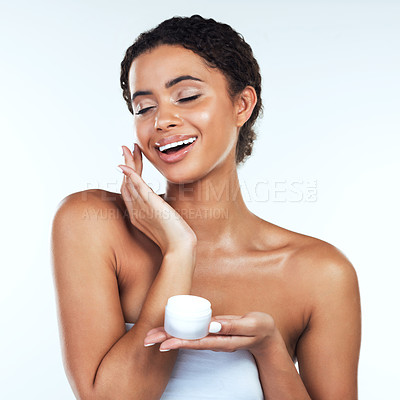 Buy stock photo Studio shot of an attractive young woman posing while applying cream to her face  against a white background