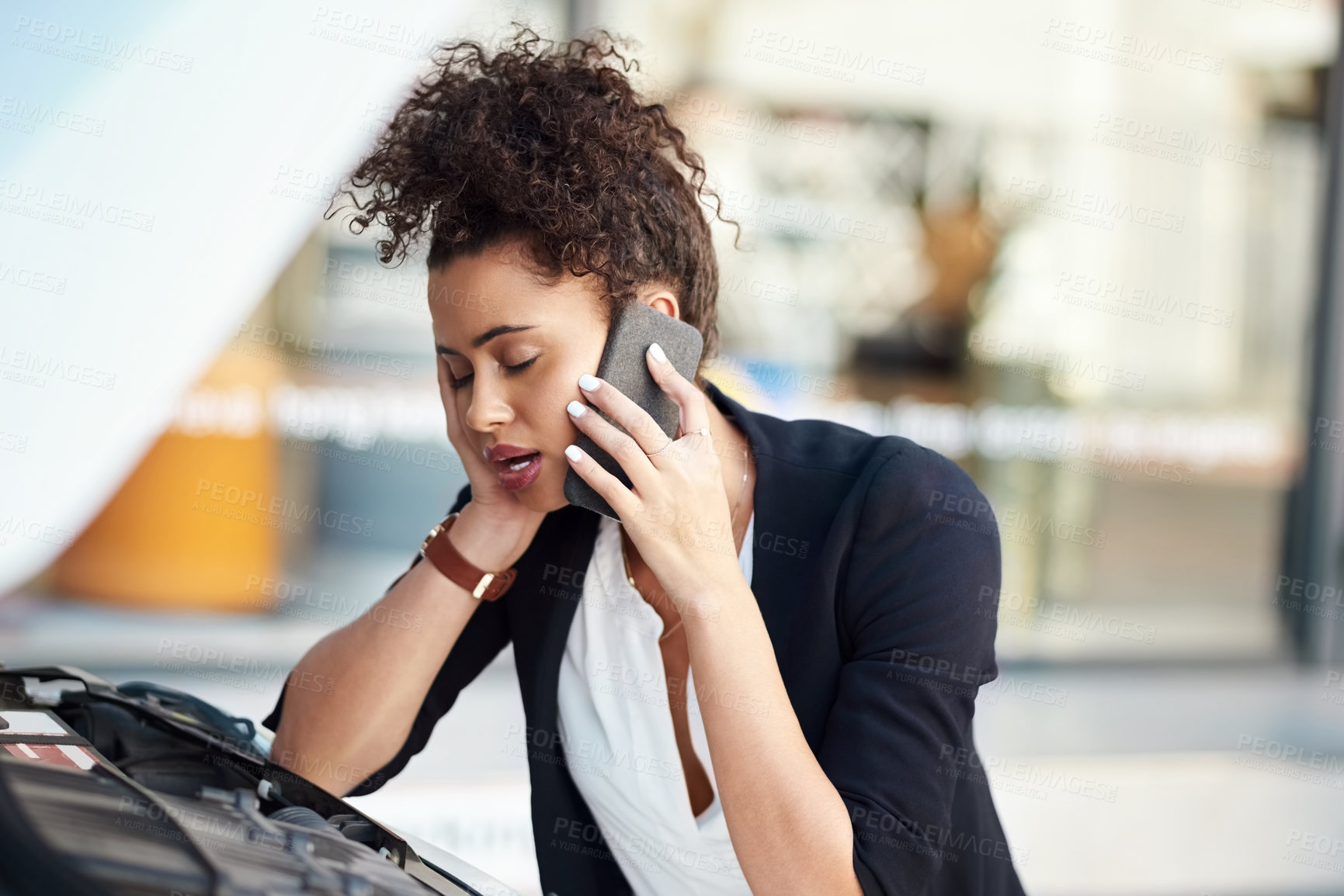 Buy stock photo Cropped shot of a frustrated young businesswoman calling roadside assistance after her car broke down