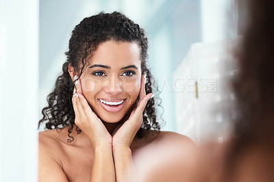 Buy stock photo Shot of a beautiful young woman looking pleased while looking in the bathroom mirror