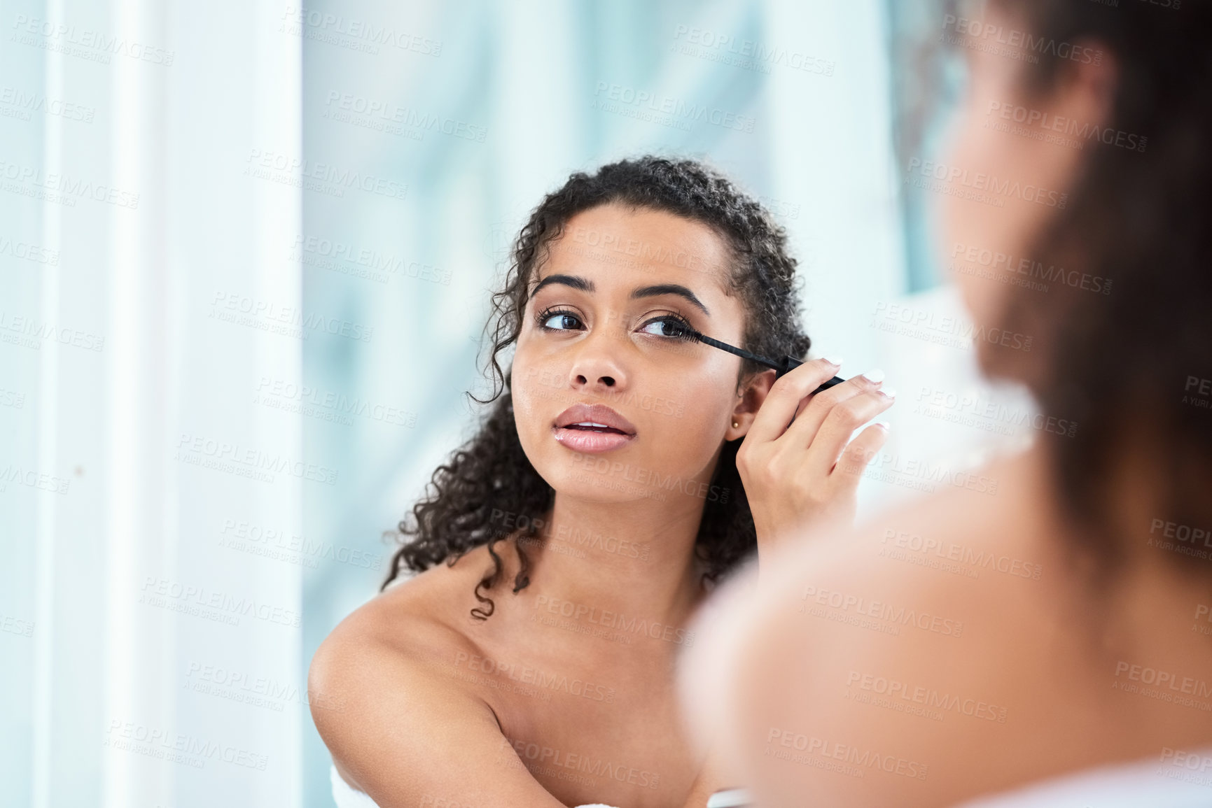 Buy stock photo Shot of a beautiful young woman applying mascara in her bathroom mirror