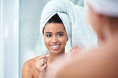 Buy stock photo Shot of a woman flossing her teeth while wearing a towel wrapped around her head