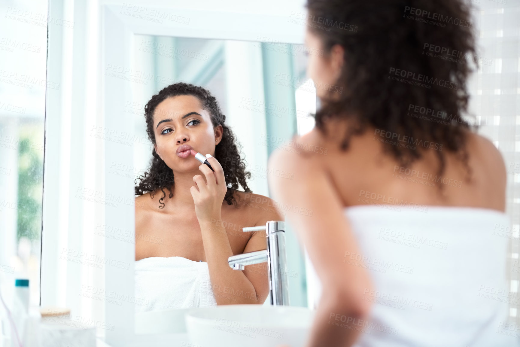 Buy stock photo Shot of a beautiful woman applying lipstick in her bathroom mirror