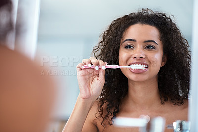 Buy stock photo Shot of a beautiful young woman brushing her teeth at home