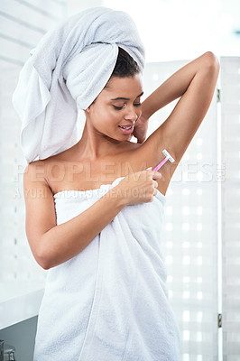 Buy stock photo Shot of an attractive young woman shaving her underarms with a razor in the bathroom