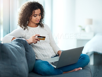 Buy stock photo Shot of a young woman holding her credit card while using her laptop at home