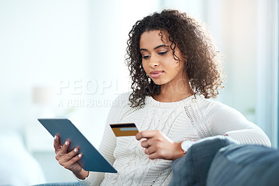 Buy stock photo Shot of a young woman holding her credit card while using a digital tablet