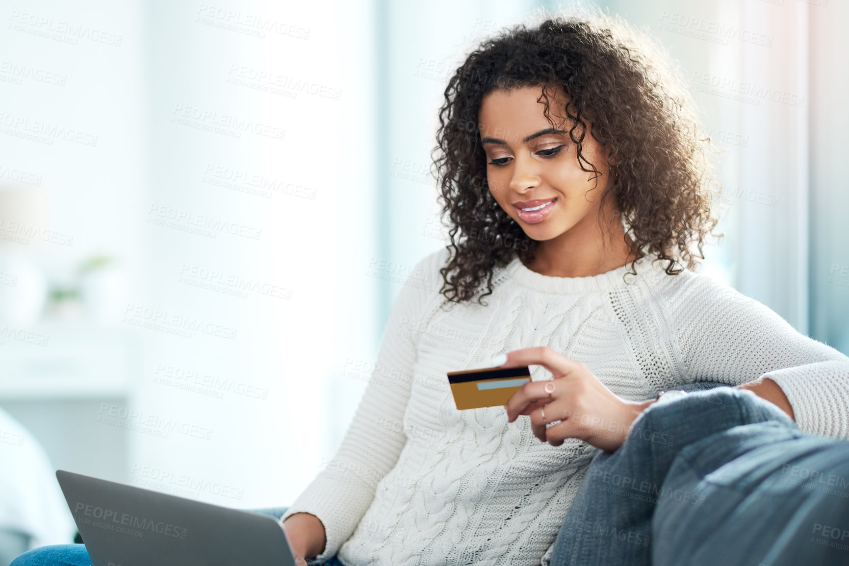 Buy stock photo Shot of a young woman holding her credit card while using her laptop at home