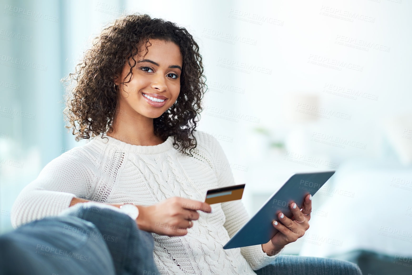 Buy stock photo Shot of a young woman holding her credit card while using a digital tablet