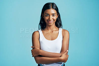 Buy stock photo Studio portrait of a beautiful young woman standing with her arms crossed against a blue background