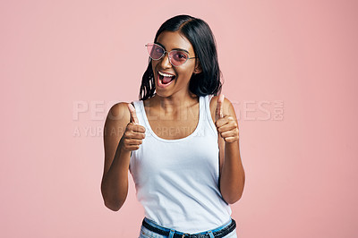 Buy stock photo Studio portrait of a beautiful young woman giving thumbs up against a pink background