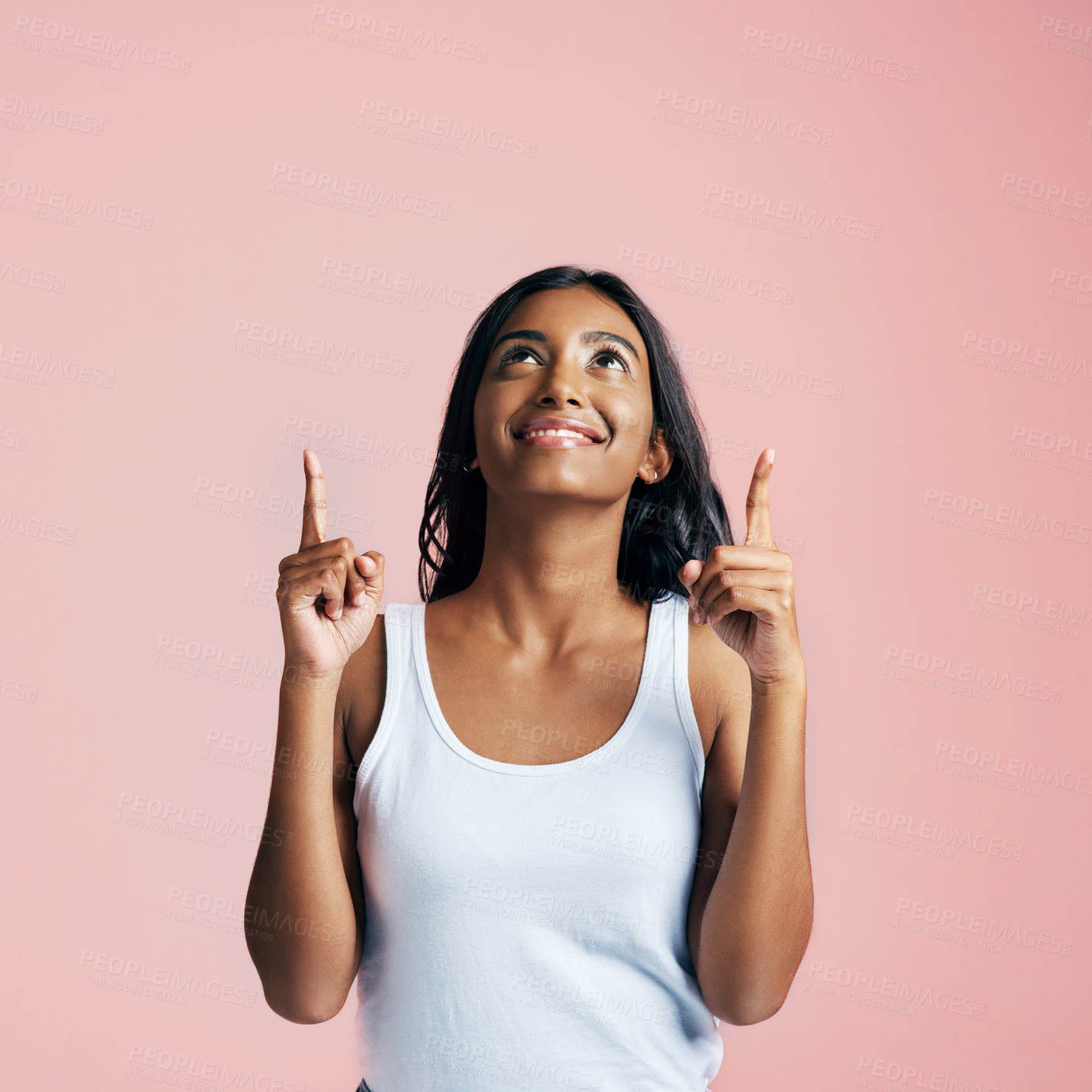 Buy stock photo Studio shot of a beautiful young woman pointing towards copyspace against a pink background