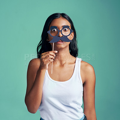 Buy stock photo Studio portrait of a beautiful young woman posing with prop glasses against a green background