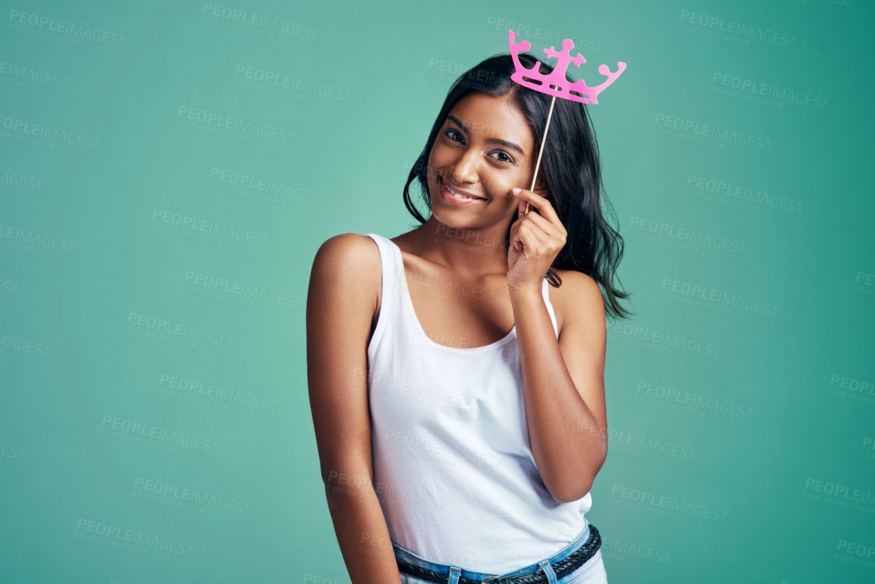 Buy stock photo Studio portrait of a beautiful young woman posing with a prop crown against a green background