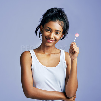 Buy stock photo Studio portrait of a beautiful young woman sucking on a lollipop against a purple background