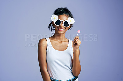 Buy stock photo Studio portrait of a beautiful young woman sucking on a lollipop against a purple background